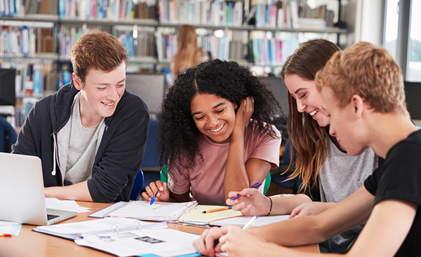 four students studying together in a library